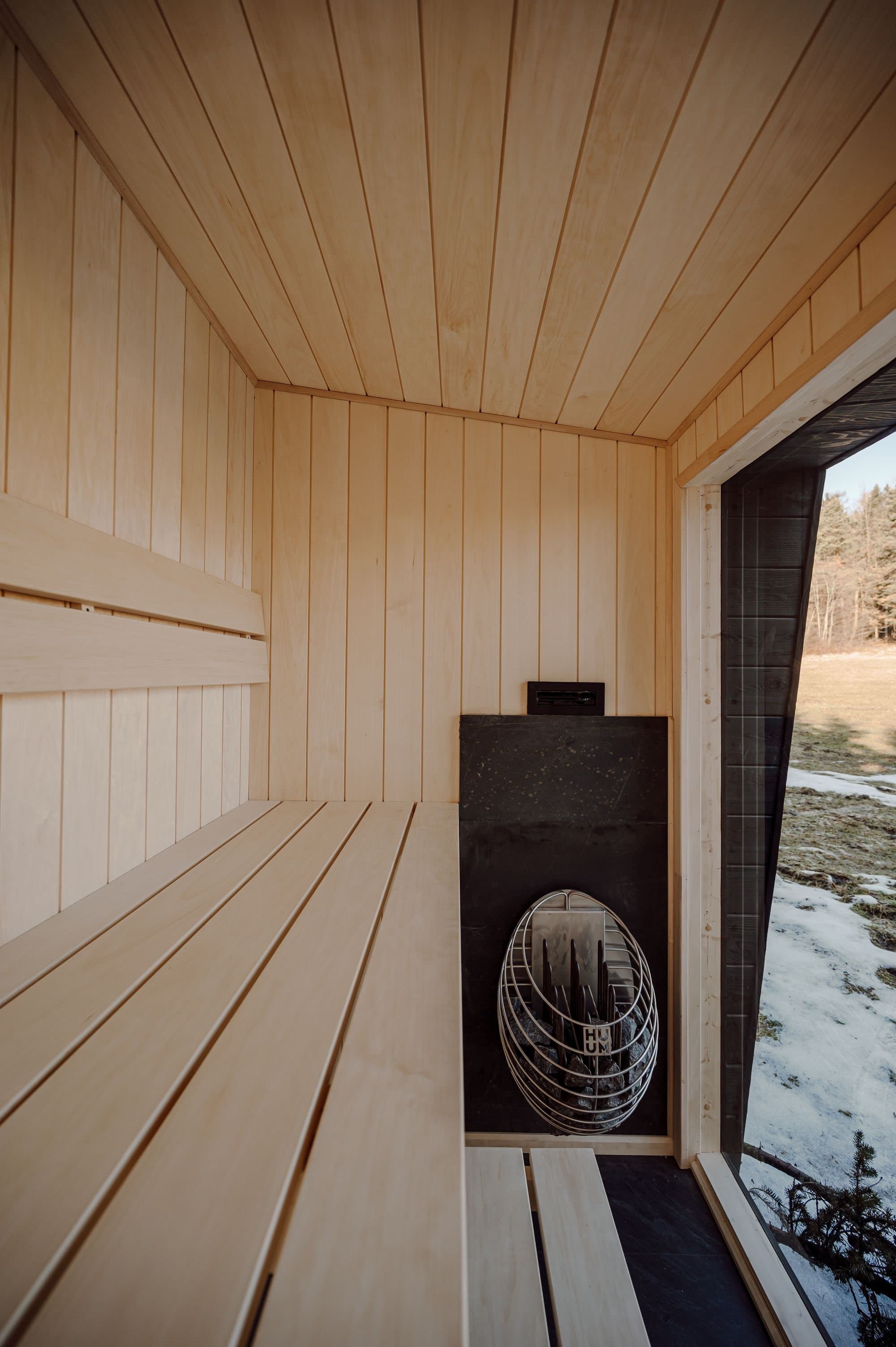 HUUM Elektroofen mit Saunasteinen in der Sauna Kaizen, Schnee durch das Fenster sichtbar