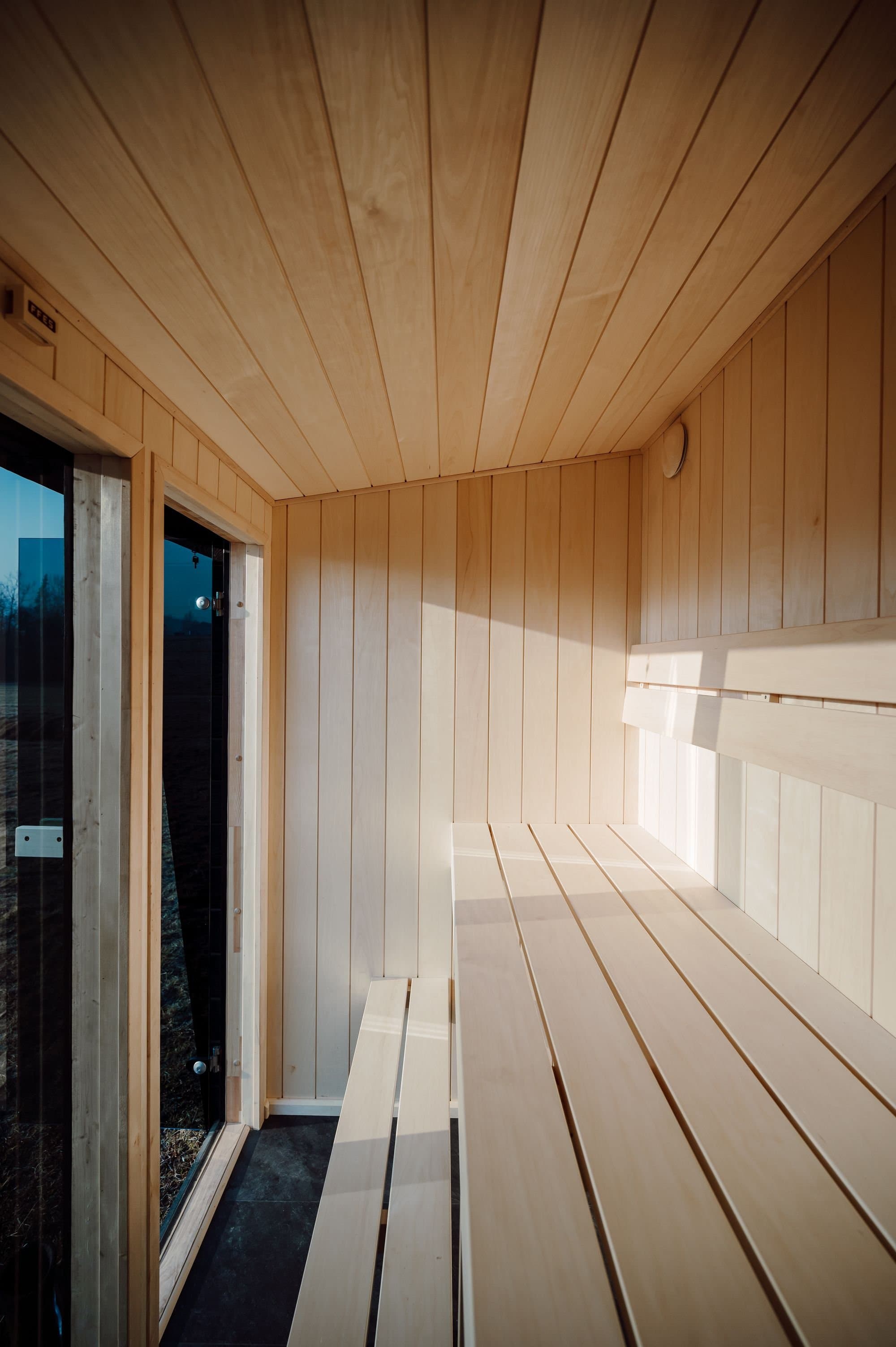 Innenraum der Sauna Kaizen mit Lindenholzwänden und zweistufiger Bank im tiefen Winterlicht