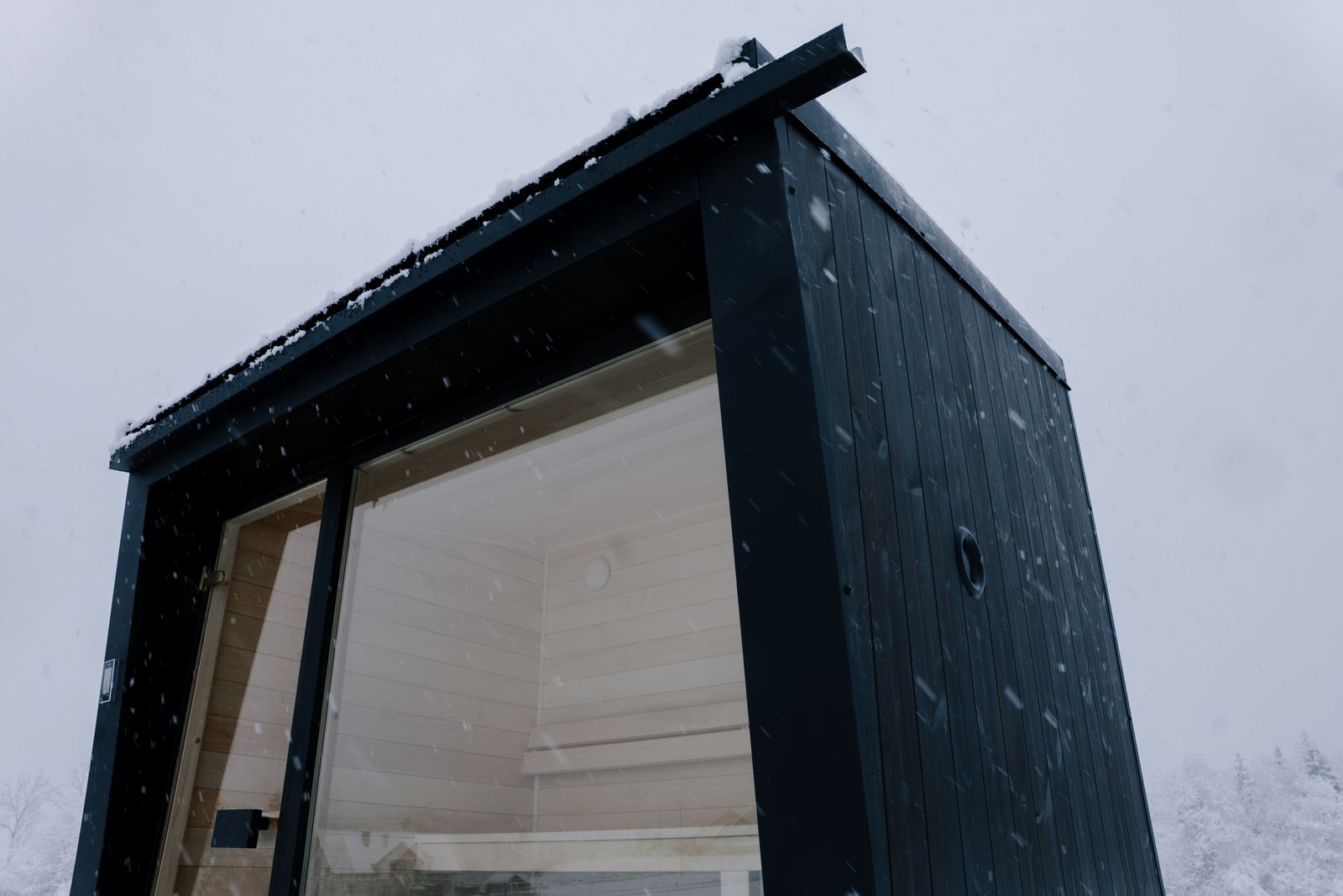 Close-up of Sauna Kaizen exterior showing charred thermo pine cladding and standing seam roof
