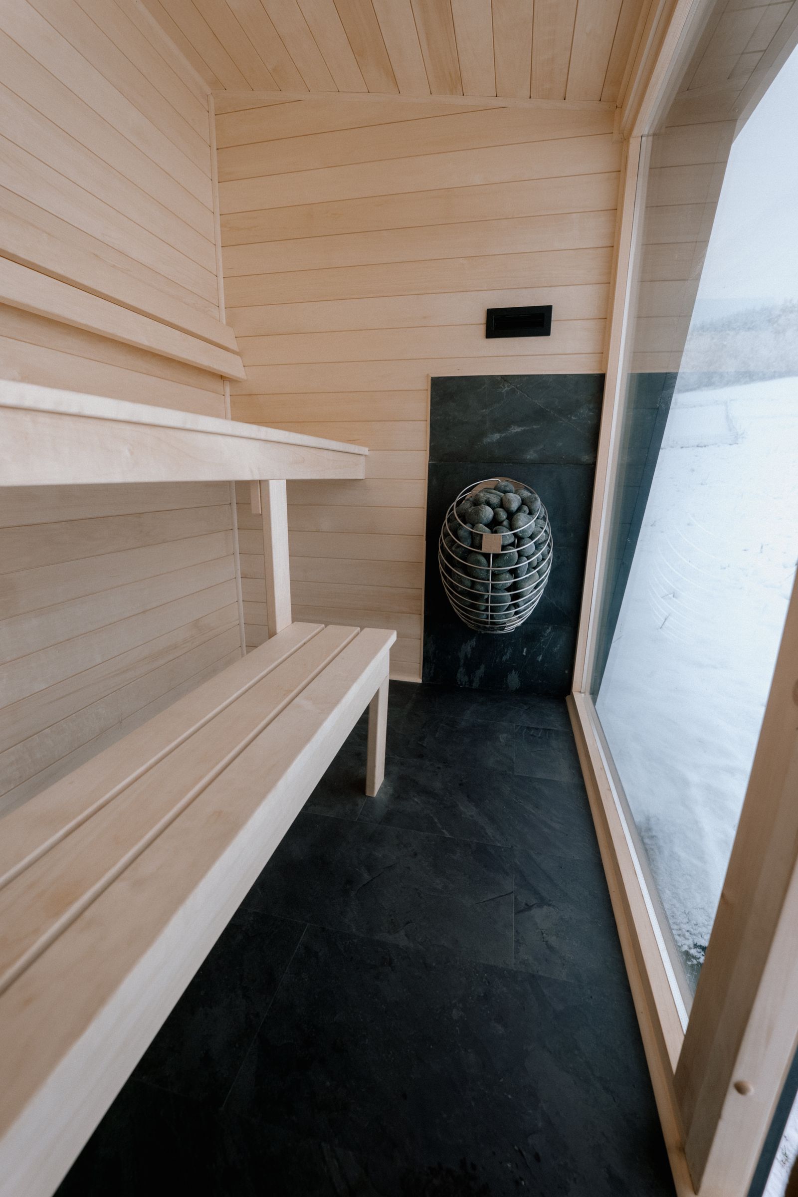 Sauna Kaizen interior showing two-tier benches, heater and full-height window